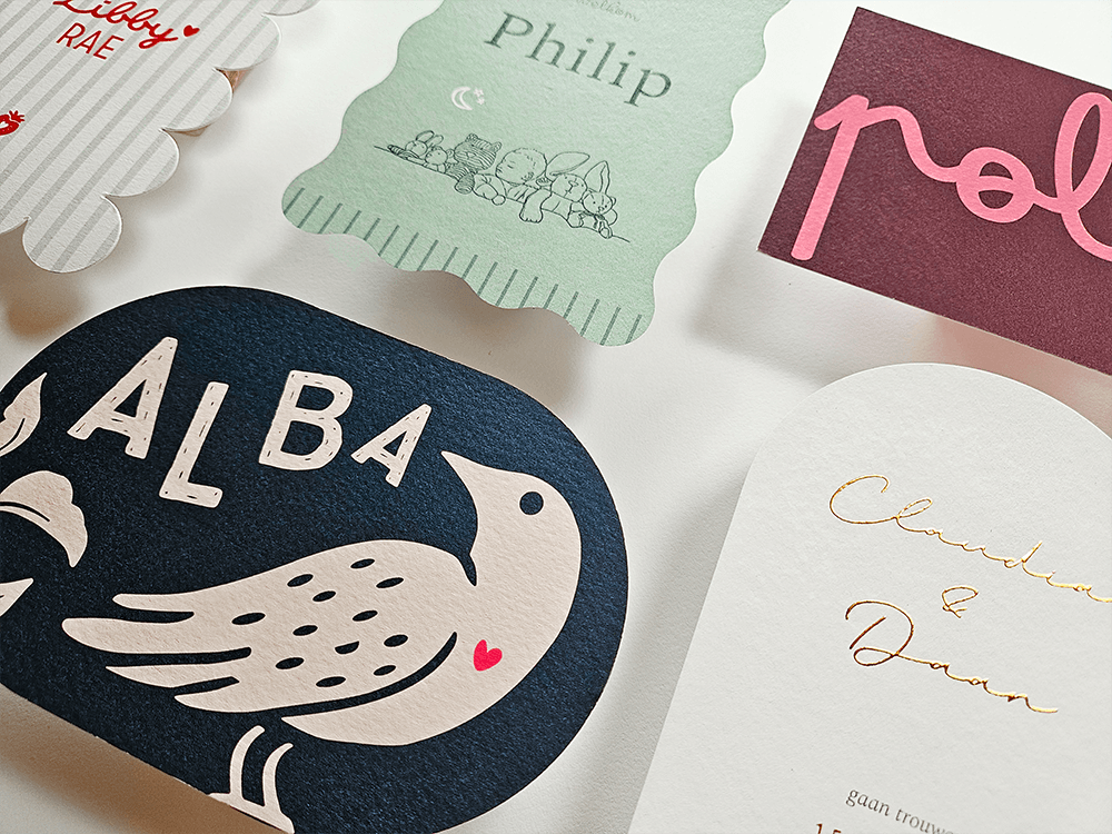 Bijzondere geboortekaartjes in verschillende vormen en kleuren, met illustraties, sierlijke letters en goudfolie van De Kaartjeswinkel.